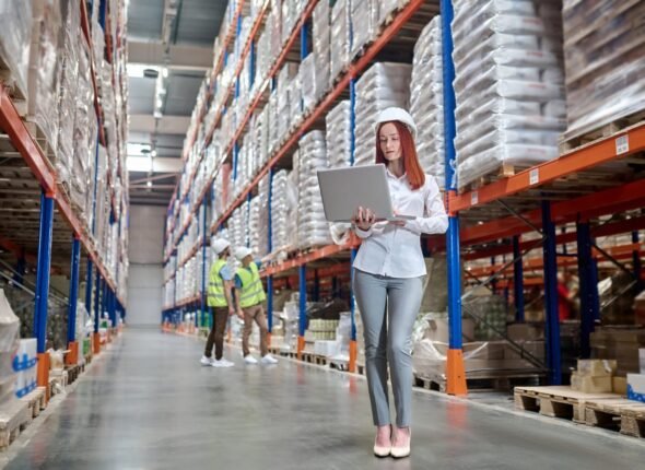 woman-standing-working-laptop-workers-warehouse-scaled